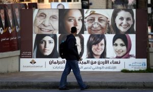 A Jordanian pedestrian passes by a Jordanian parliamentary campaign poster, in Amman