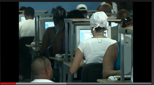 Screengrab from Avanza Cuba episode on Cyber Cafes, shows a row of computers in a cyber cafe with people sitting at each one