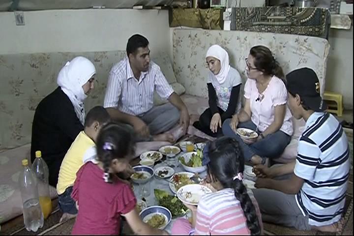Family sits around table with Iftar meal, celebrating Ramadan.