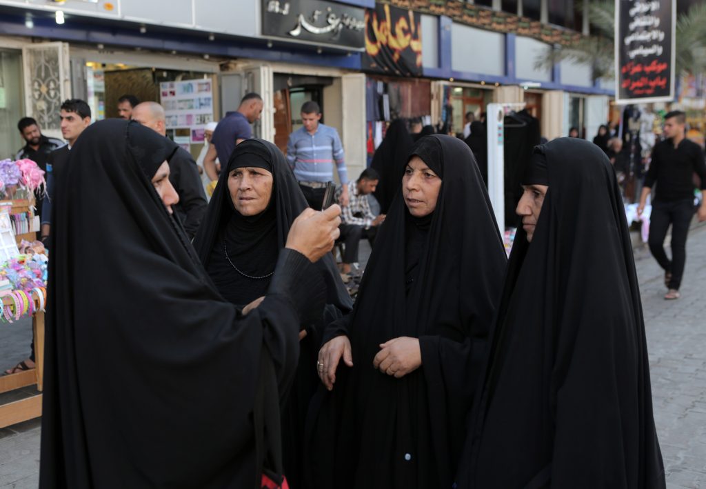 An Iraqi woman takes a photograph of family members on her mobile phone in Baghdad, Iraq, Saturday, Nov. 1, 2014. (AP Photo/Khalid Mohammed)