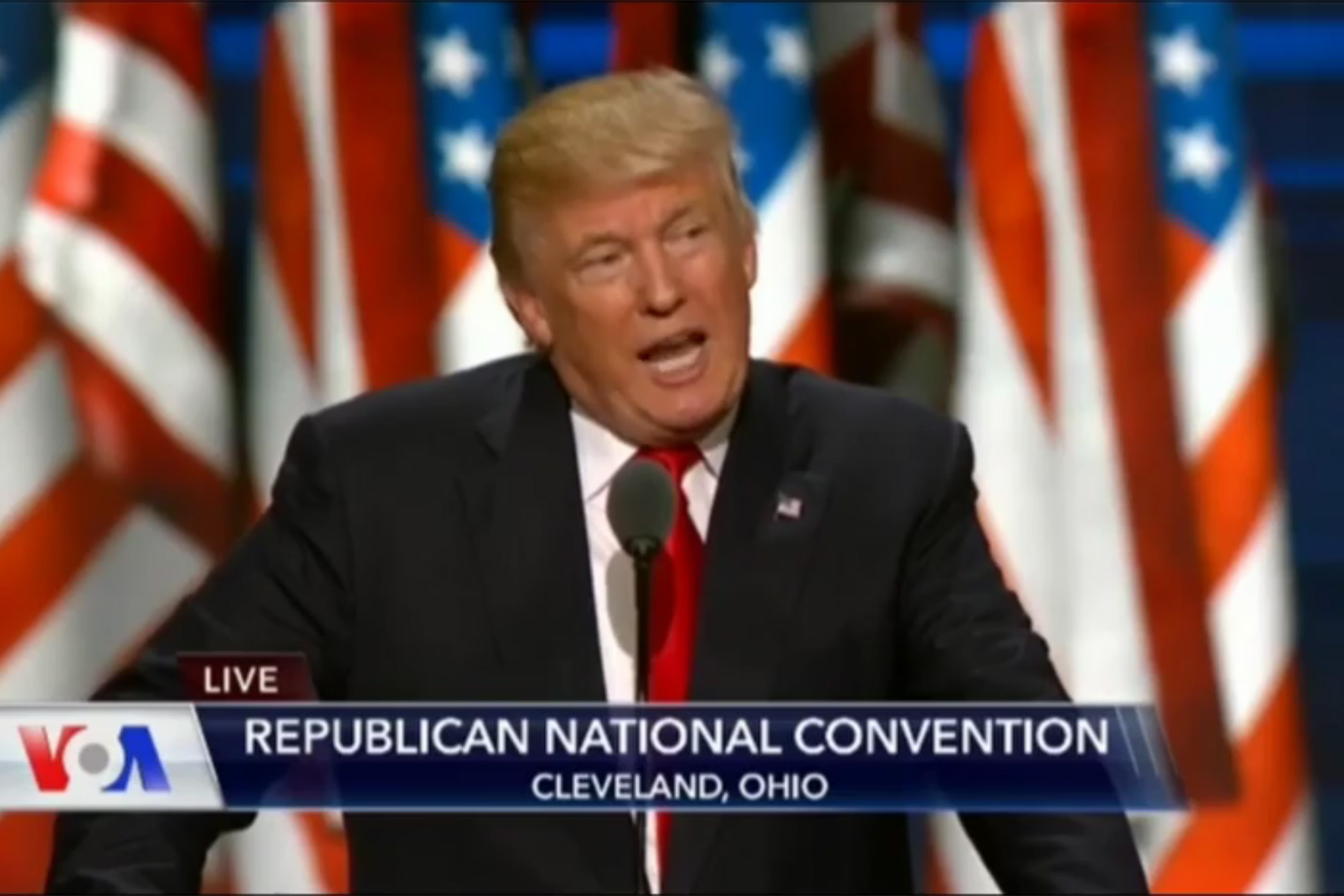 Donald Trump speaking in front of several American flags in the background