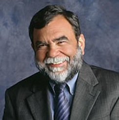 Formal portrait of an older bearded man in a grey suit