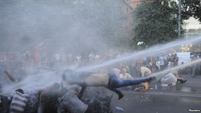 Protestors being knocked down by a jet of water.